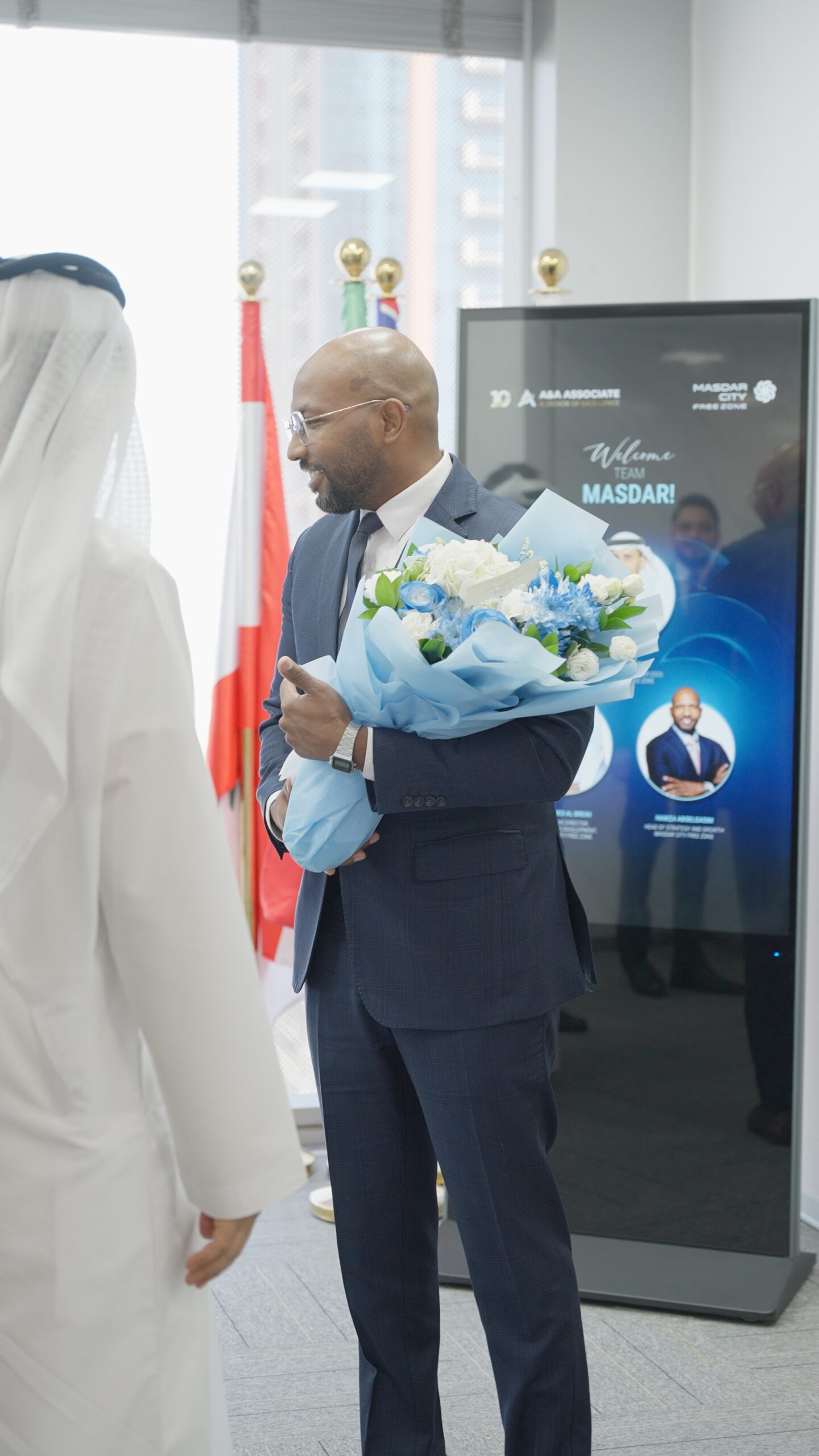 Official group photo of A&A Business Setup Experts team and Masdar City Abu Dhabi delegation at Dubai office with flowers